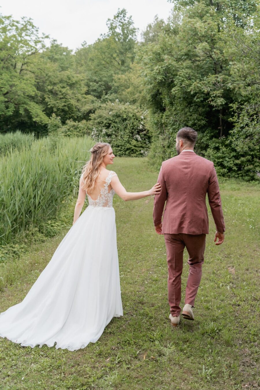 Brautpaar spaziert durch grünen Gartenweg