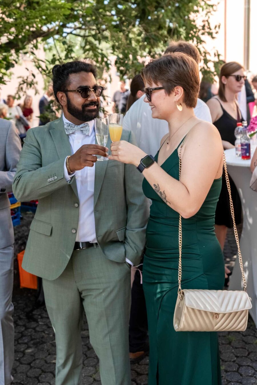 Gäste stoßen bei Hochzeit im Sommergarten an