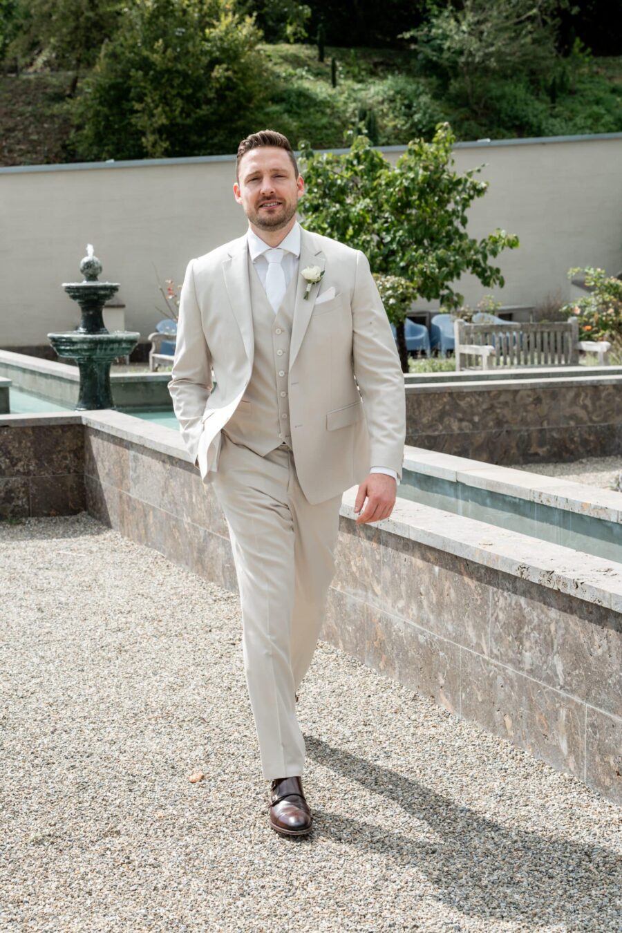 Bräutigam im Garten vor Springbrunnen