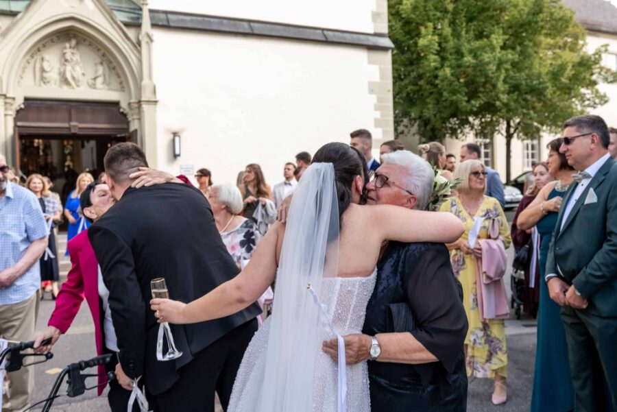 Brautpaar begrüßt Gäste vor der Kirche