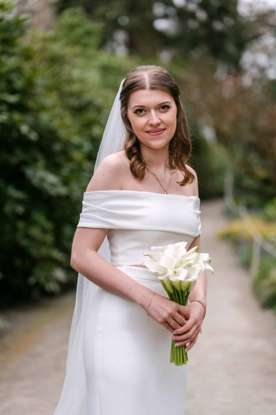Hochzeit Insel Mainau Bodensee – Heiraten am Bodensee 154 Braut im weißen Kleid mit Calla-Strauß im Garten