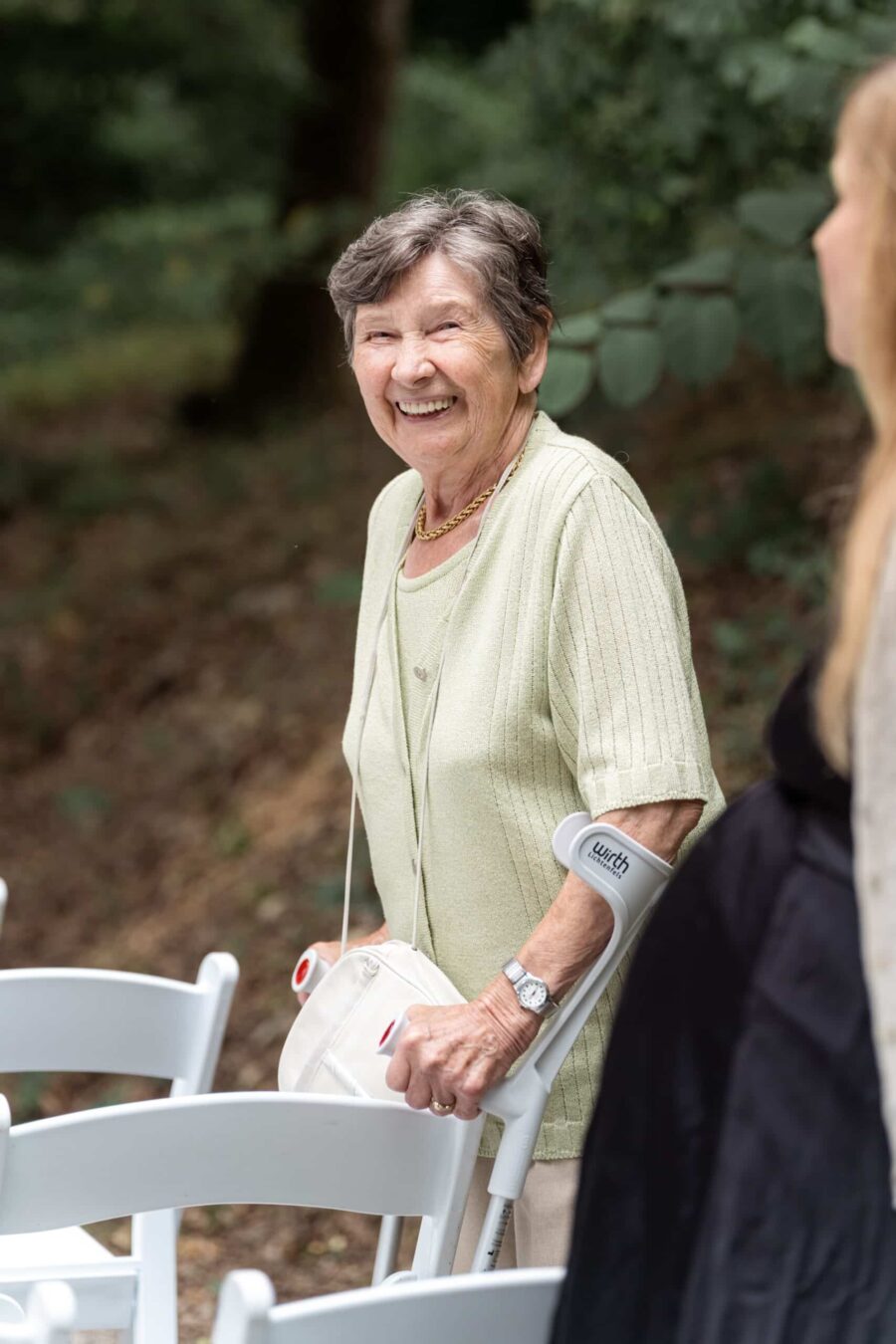 Ältere Dame lächelnd im Garten bei Hochzeit.