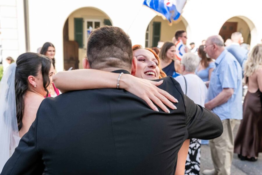 Gäste umarmen sich bei Hochzeitsempfang im Freien.