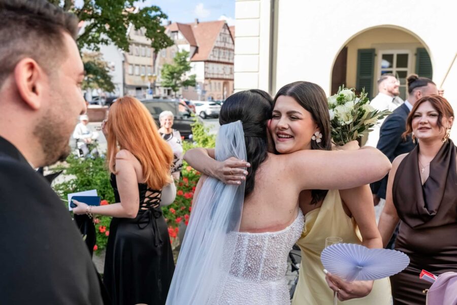 Braut umarmt Gast im Freien bei der Hochzeit.