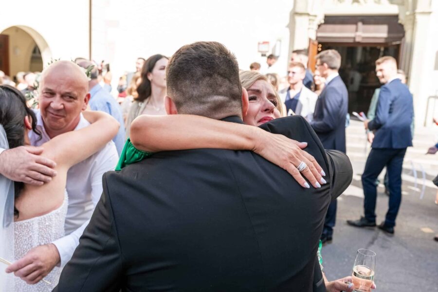 Gäste umarmen sich bei Hochzeitsfeier im Freien