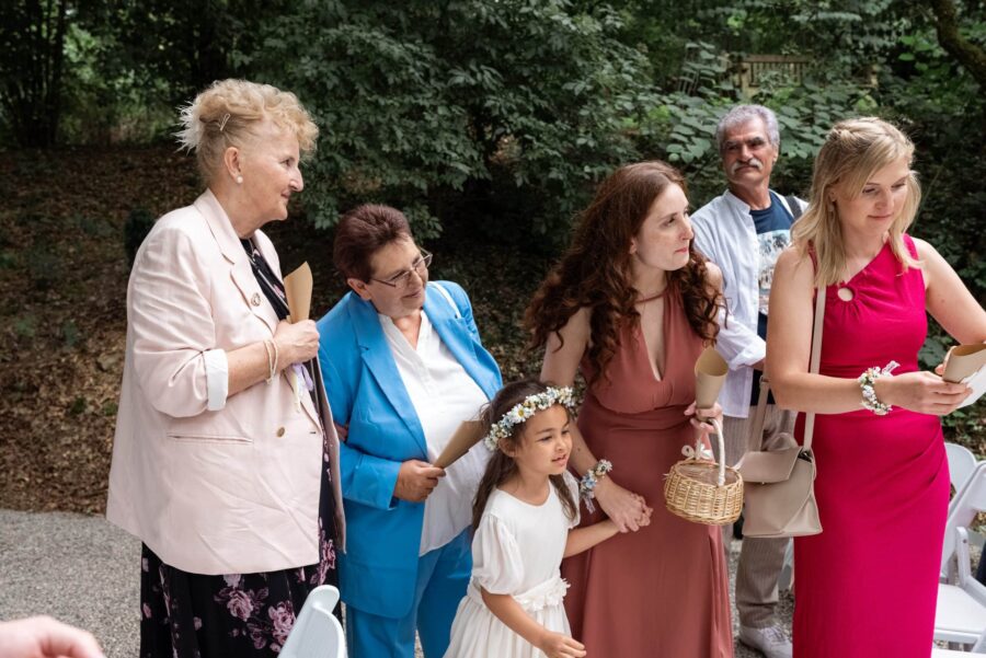 Gäste in Festkleidung bei Hochzeit im Garten.