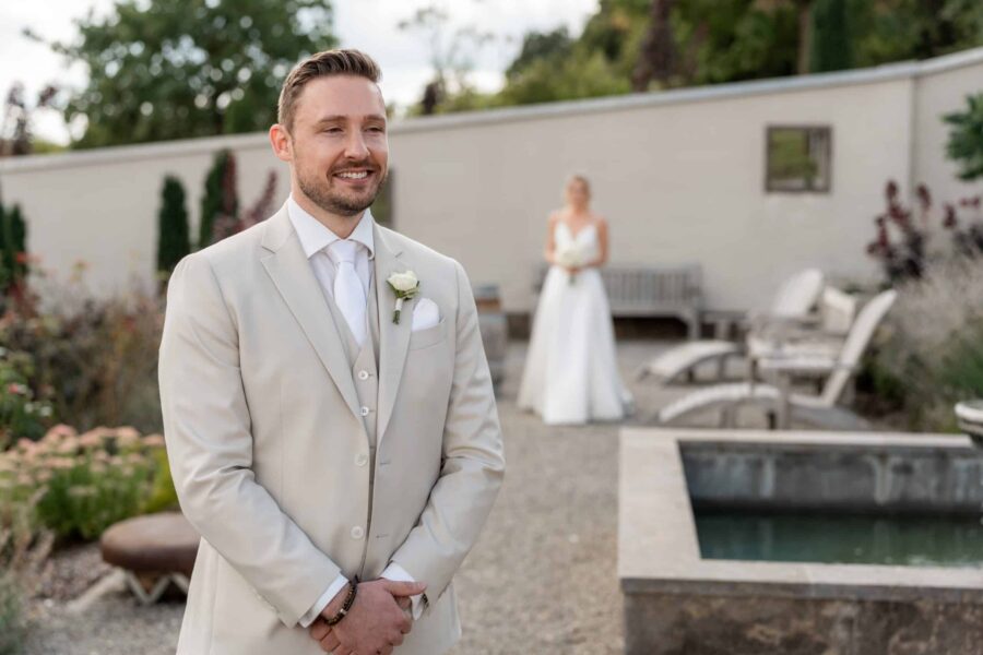 Bräutigam im Garten mit Braut im Hintergrund