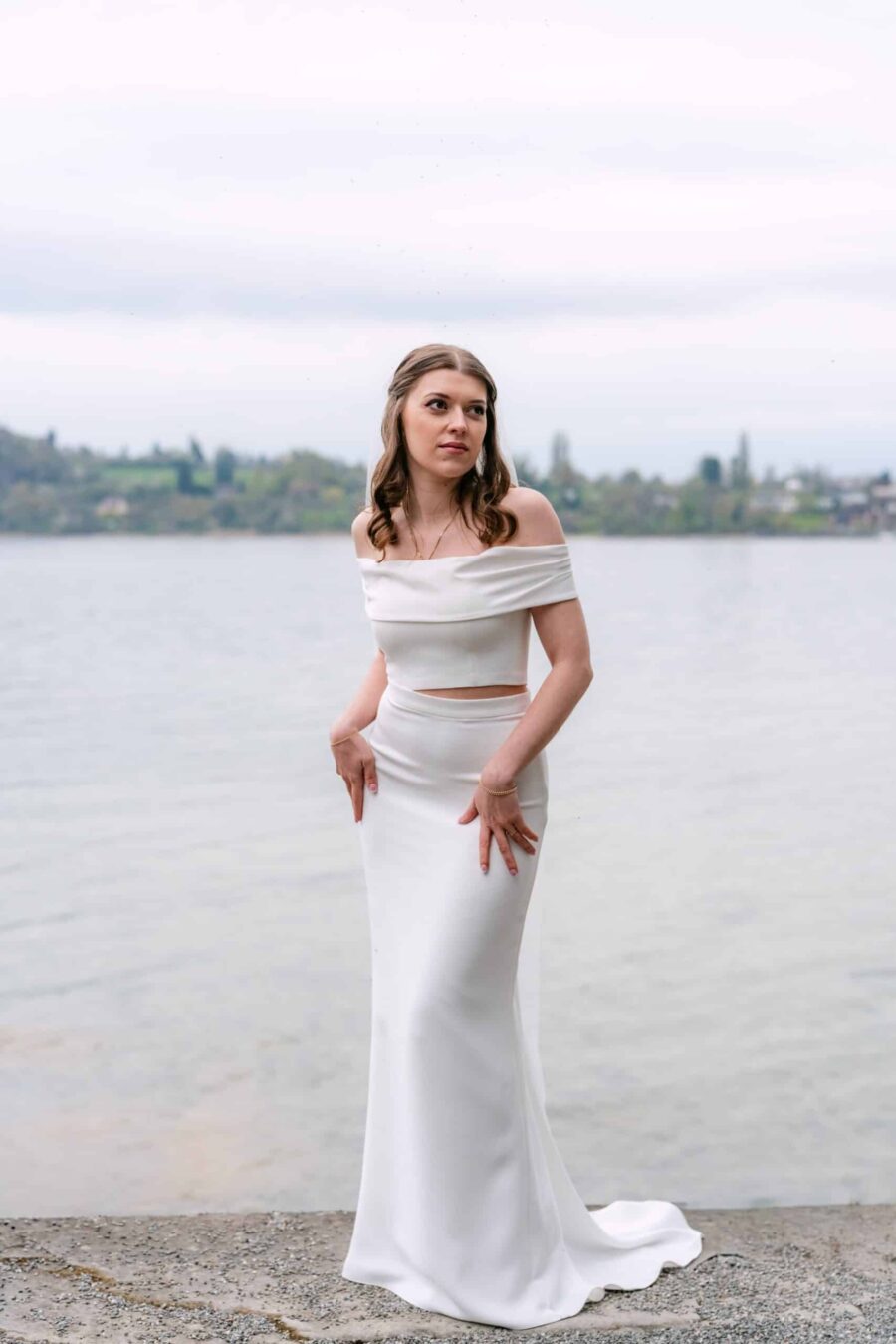 Braut im schulterfreien Kleid am Seeufer