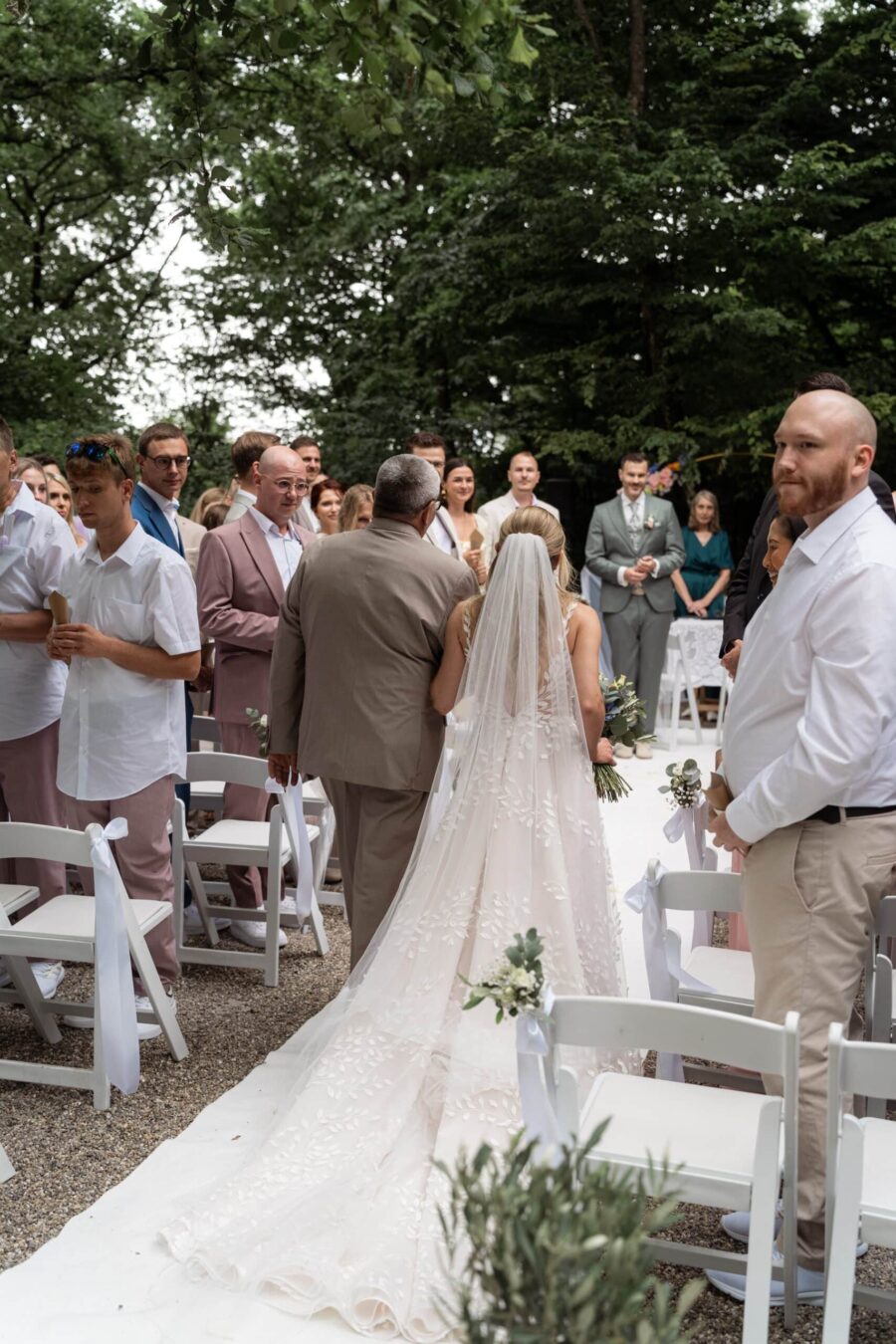 Braut geht mit Begleitung zum Altar im Freien