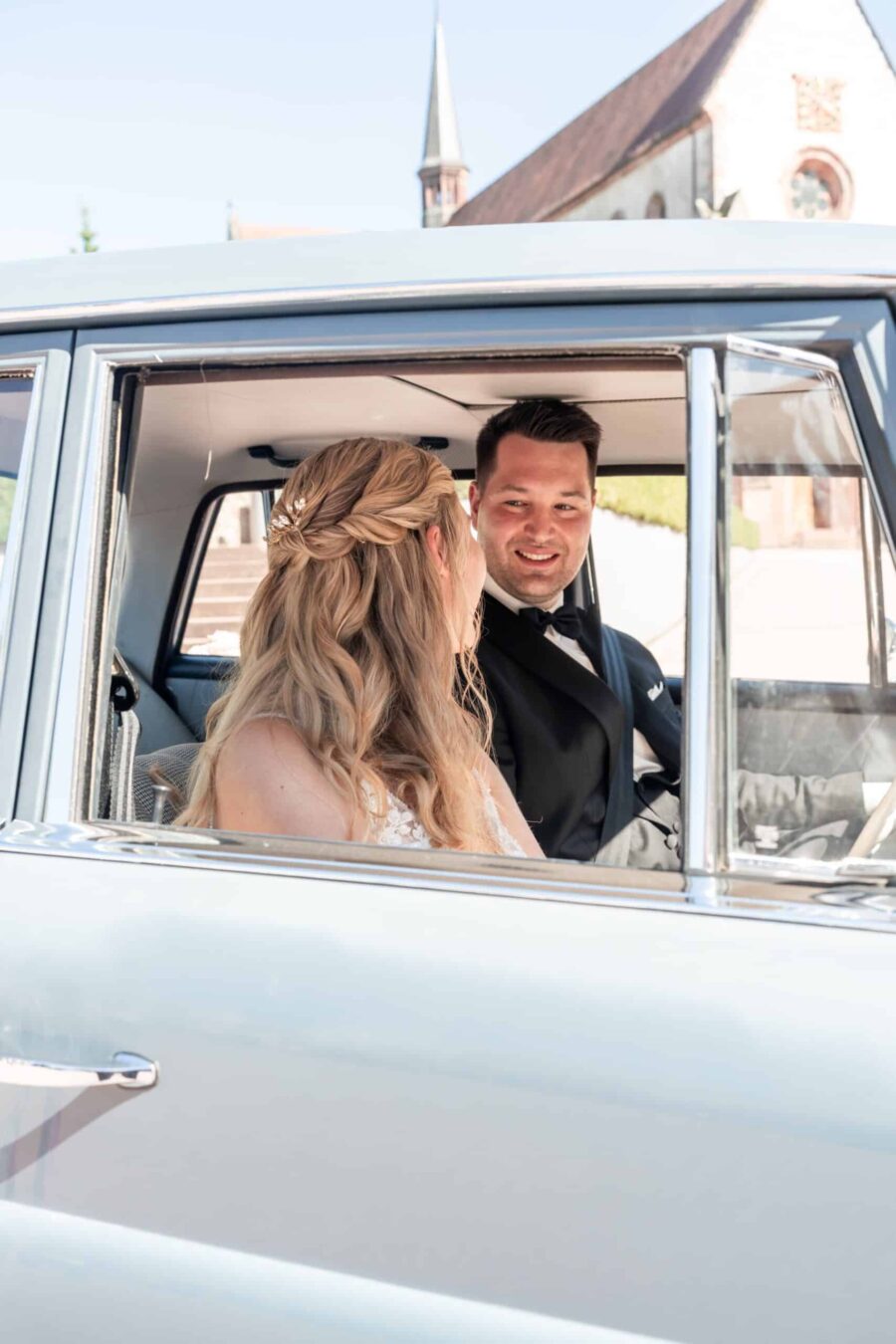 Brautpaar im Auto vor einer Kirche