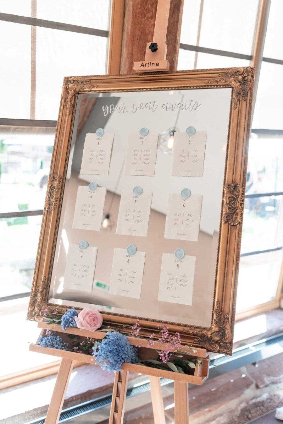 Sitzplan in goldnem Rahmen mit Blumen dekoriert