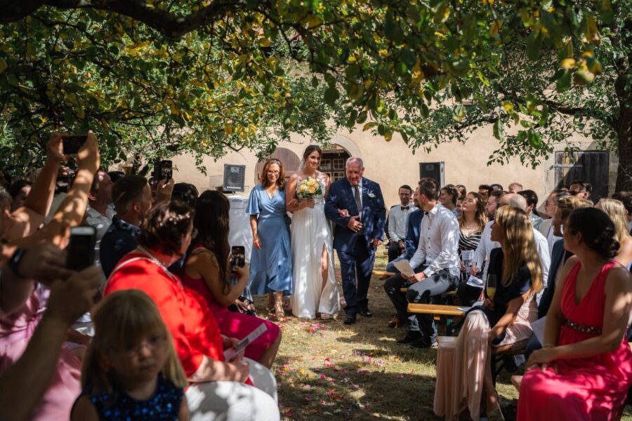 Braut mit Eltern beim Hochzeitseinzug im Freien