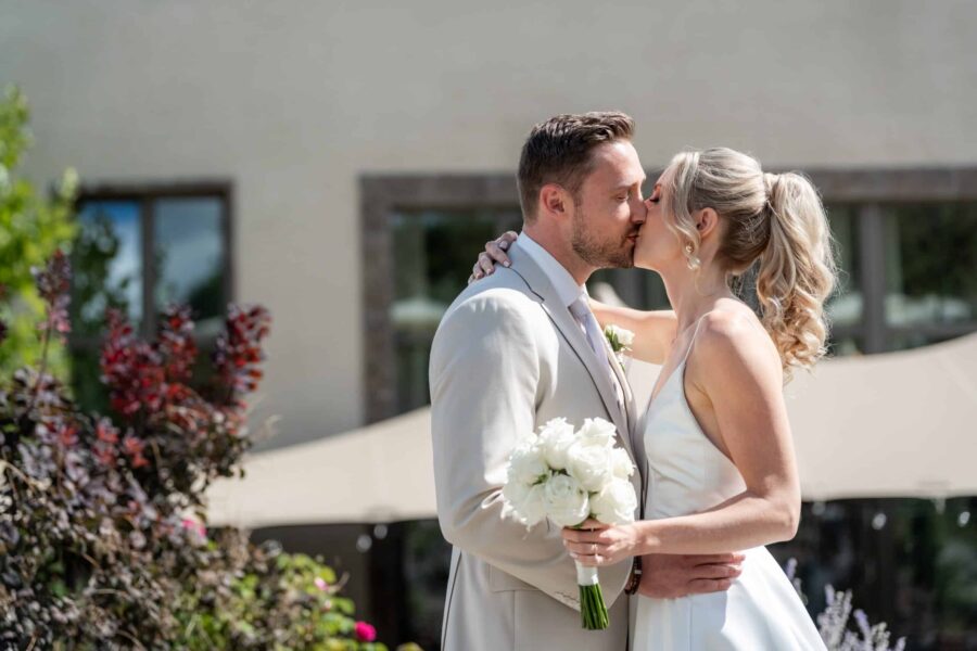 Hochzeit Villa Oriental | Editorial Summer Vibes & Live Cooking 313 Brautpaar küsst sich vor Gebäude im Garten
