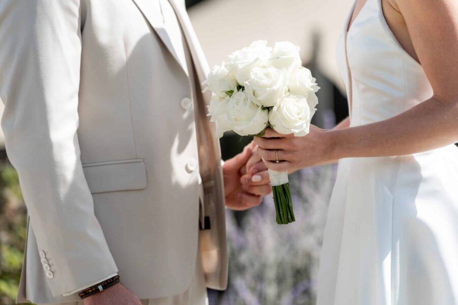 Brautpaar hält Hände mit weißen Rosen