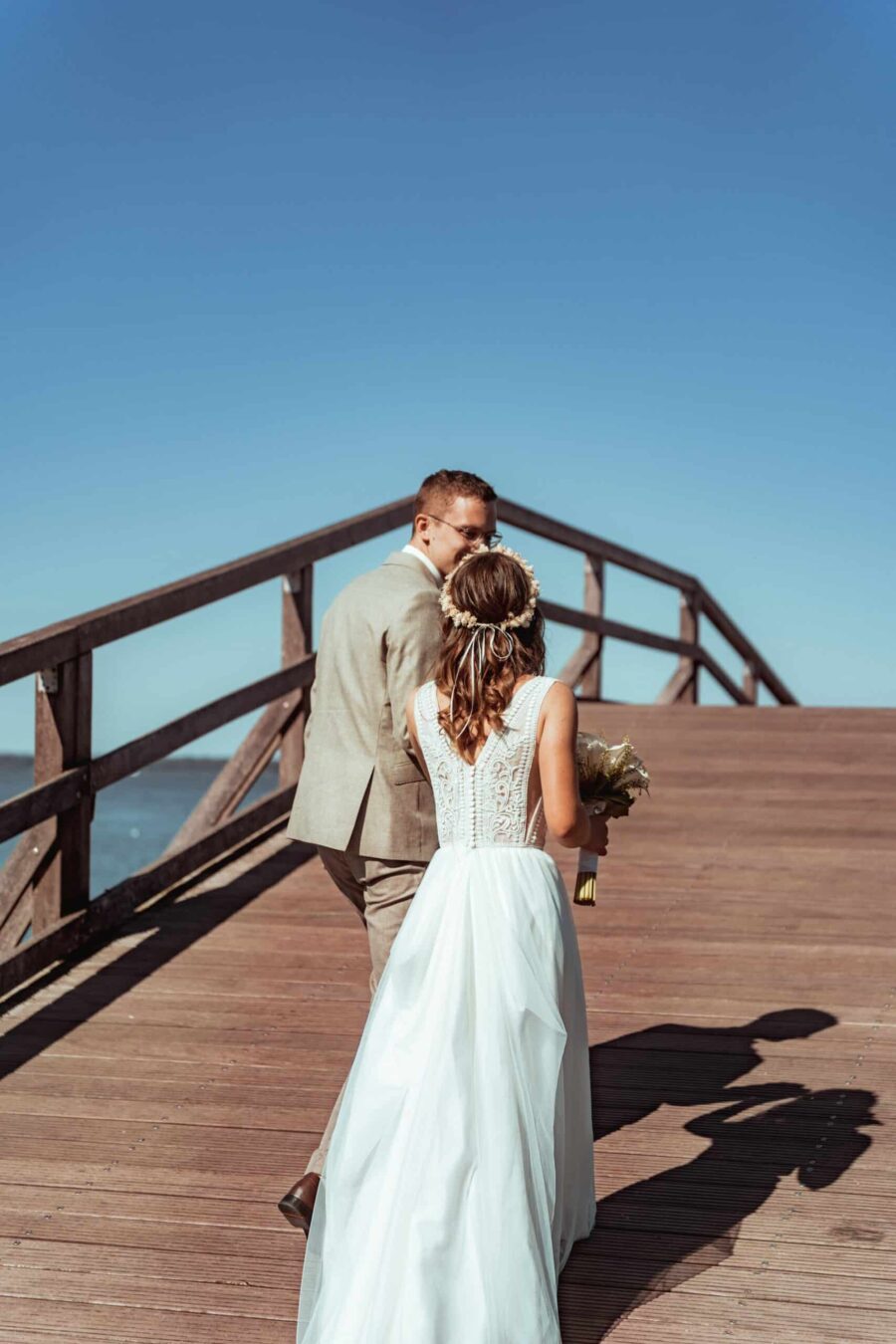 Brautpaar auf Steg mit Meerblick im Sonnenschein