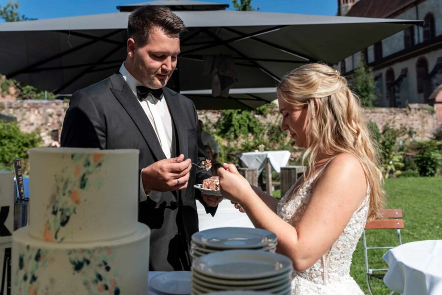Brautpaar schneidet Hochzeitstorte im Garten an