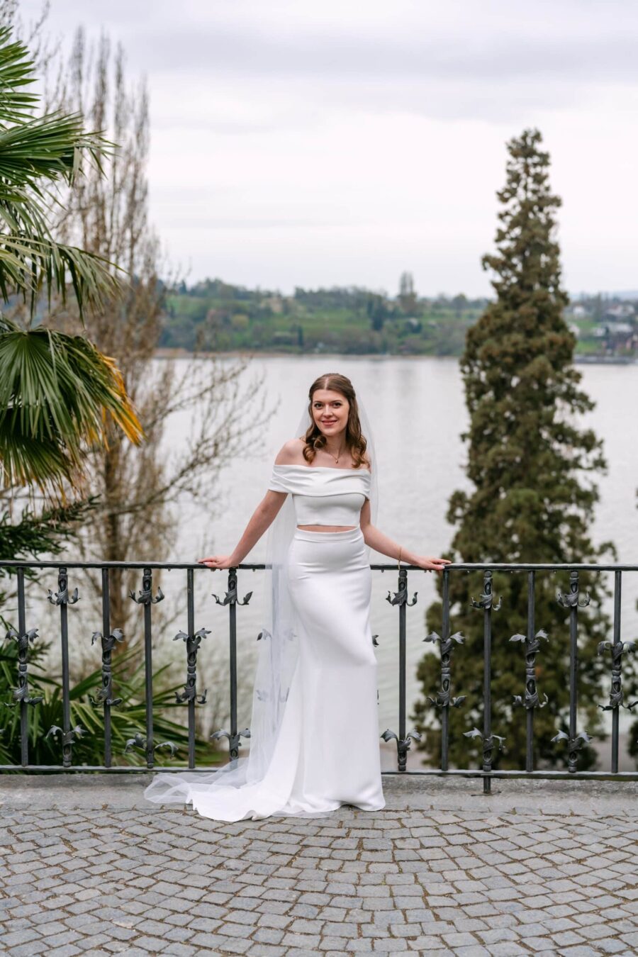 Braut im Hochzeitskleid auf Terrasse am See