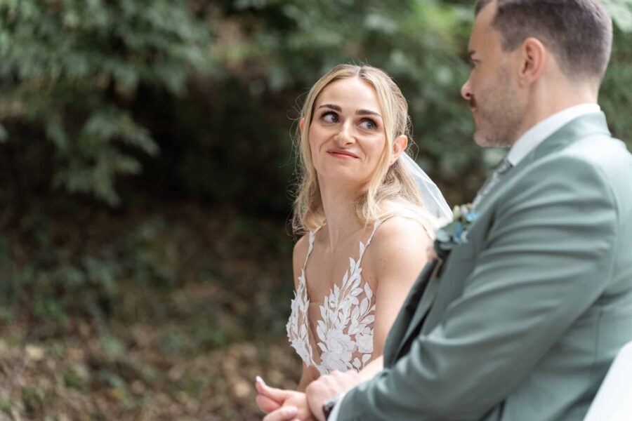 Brautpaar im Garten lächelnd einander zugewandt