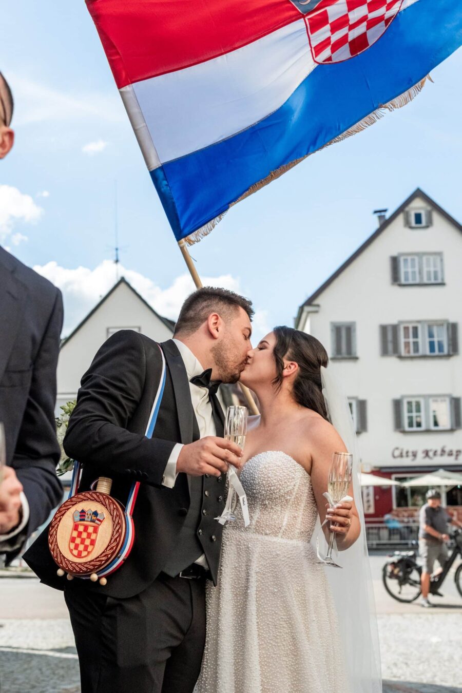 Brautpaar küsst sich mit kroatischer Flagge im Hintergrund