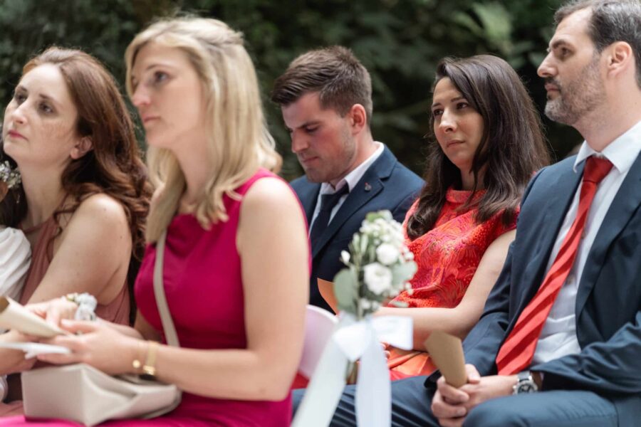 Gäste sitzen bei Hochzeitszeremonie im Freien.