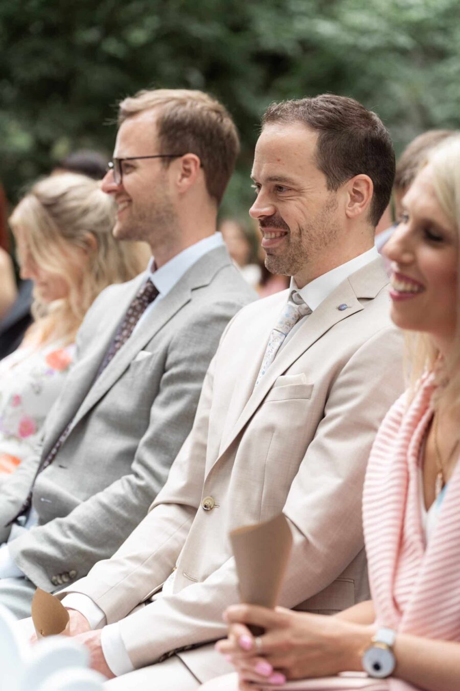 Gäste sitzen bei einer Hochzeit im Freien.