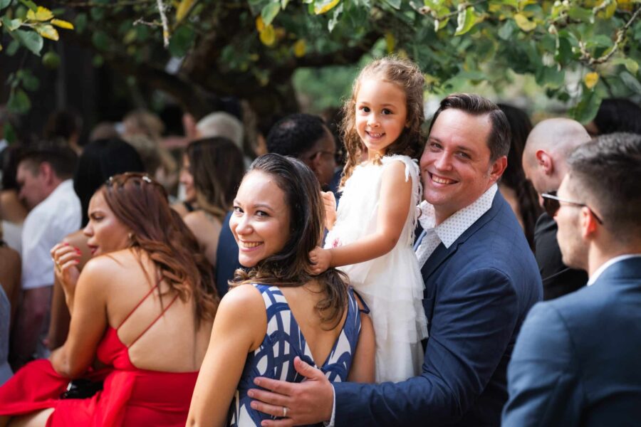 Gäste lächeln bei Gartenhochzeit im Sommer.