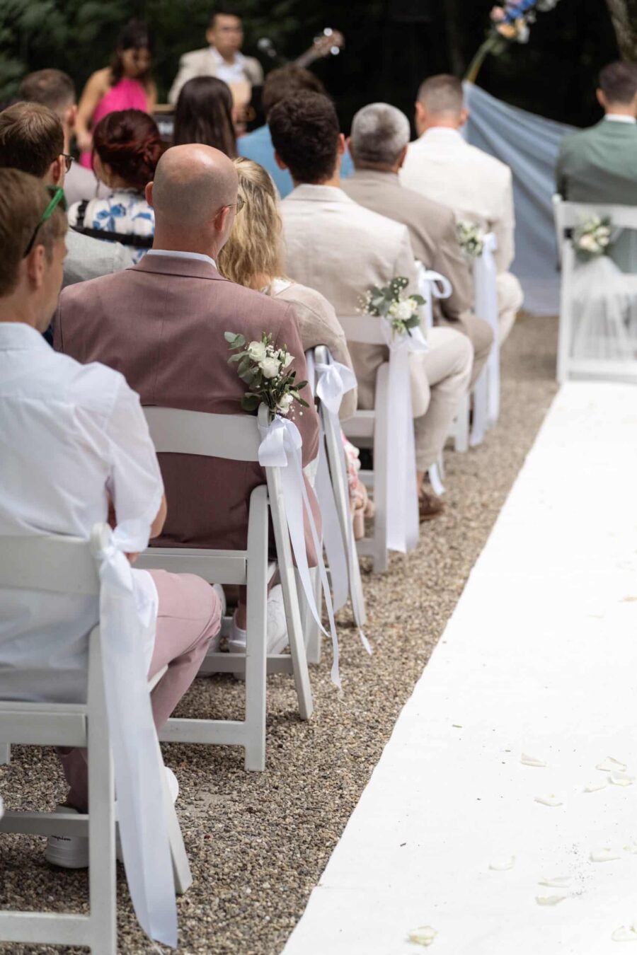 Gäste sitzen bei einer Hochzeitszeremonie im Freien