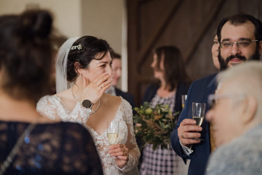 Brautpaar und Gäste bei Sektempfang in festlichem Raum