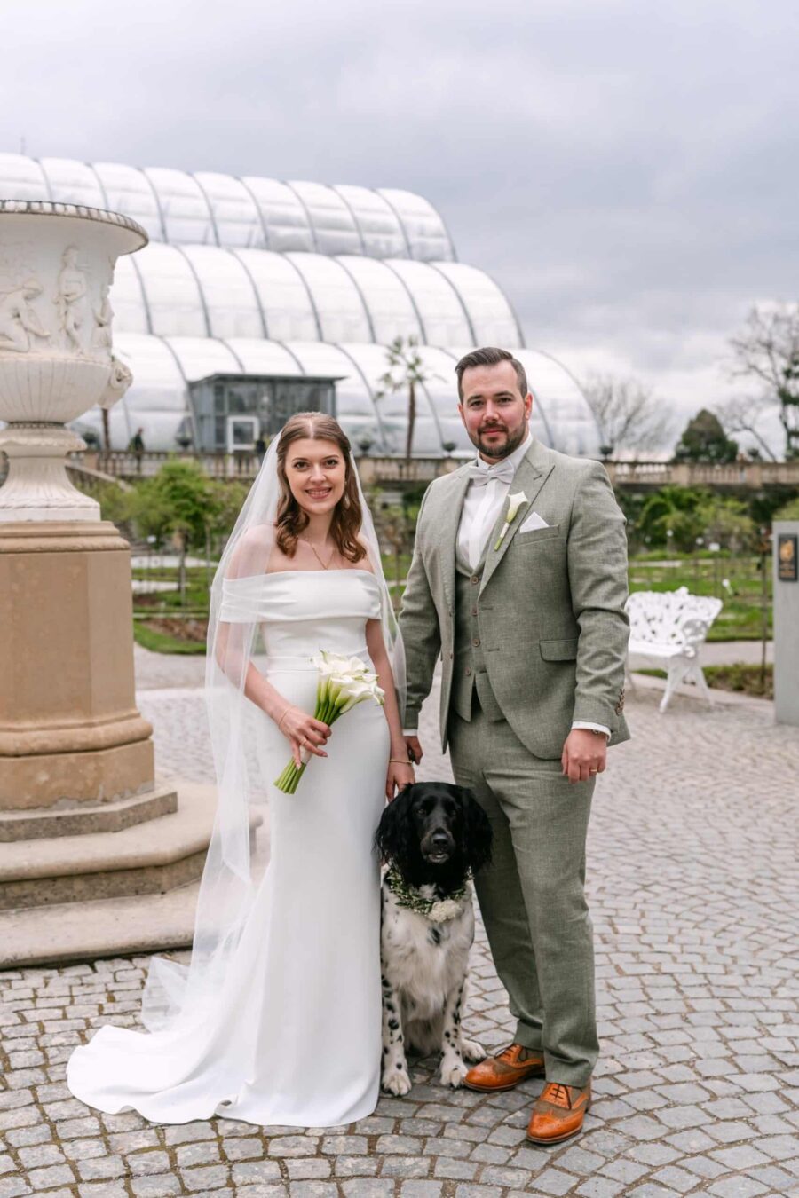 Brautpaar mit Hund vor Gewächshaus im Garten