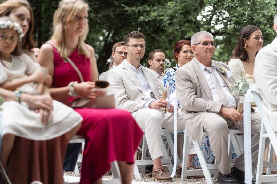 Hochzeitsgäste sitzen im Garten bei der Trauung.