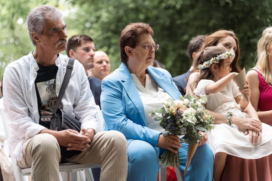 Gäste sitzen mit Blumenstrauß bei Hochzeitsfeier draußen
