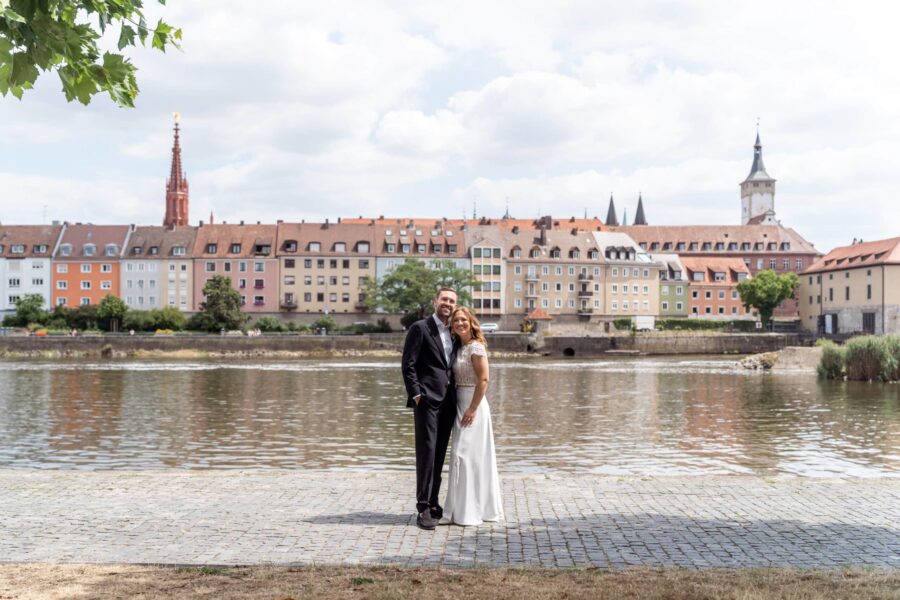 Brautpaar am Flussufer vor Stadtkulisse