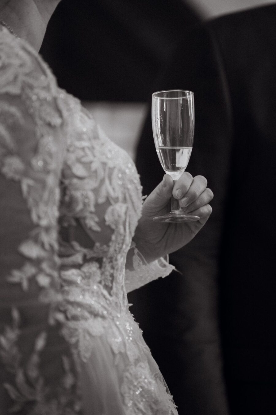 Braut hält Sektglas in Spitzenkleid