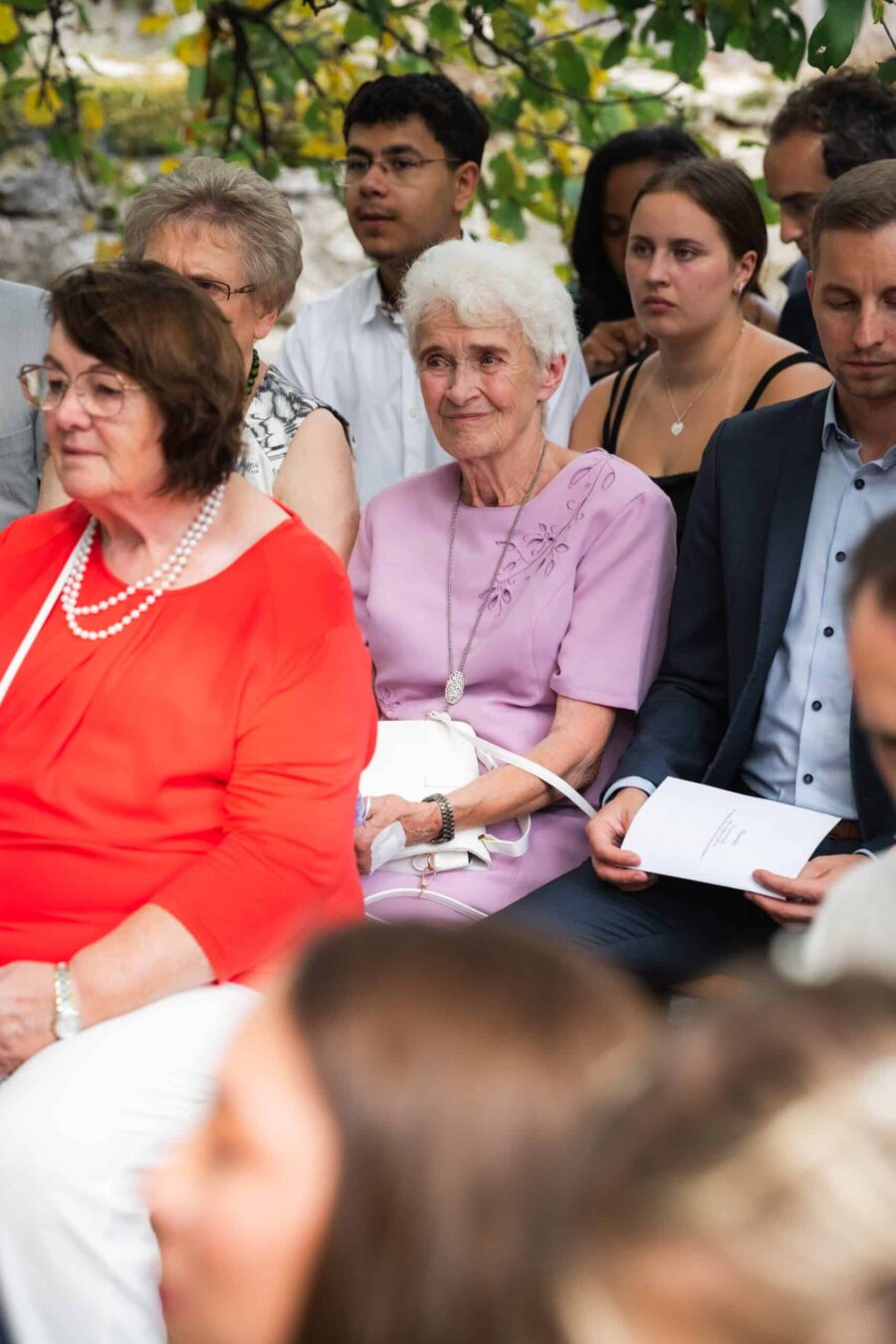 Gäste sitzen bei Hochzeitszeremonie im Freien.