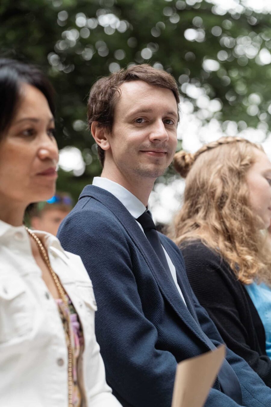 Gäste sitzen bei Hochzeitszeremonie im Freien