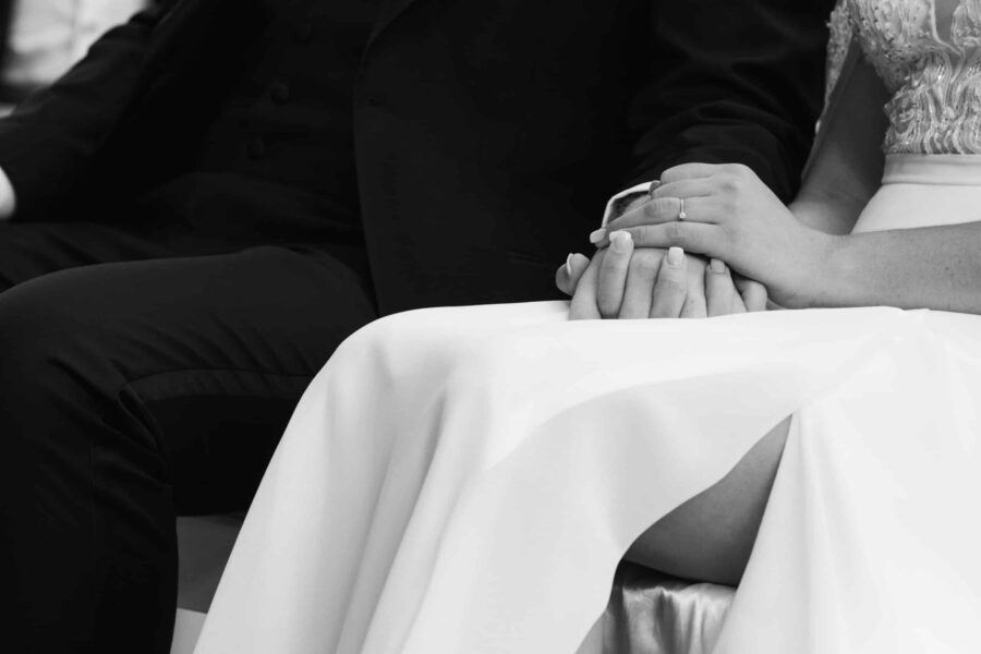 Hände des Brautpaars im Hochzeitskleid und Anzug