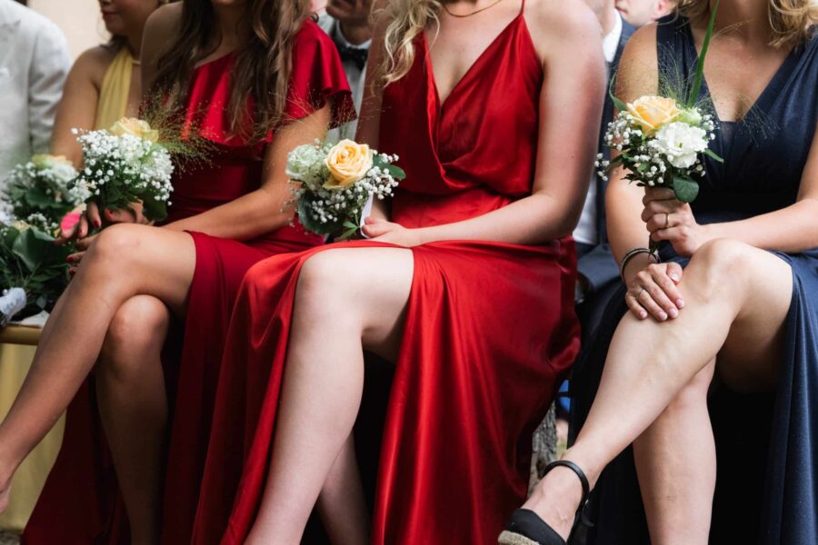 Gäste in eleganten Kleidern mit Blumensträußen.