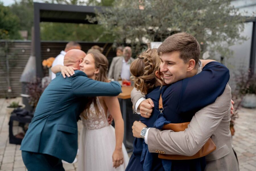Gäste umarmen sich bei Hochzeitsfeier im Freien
