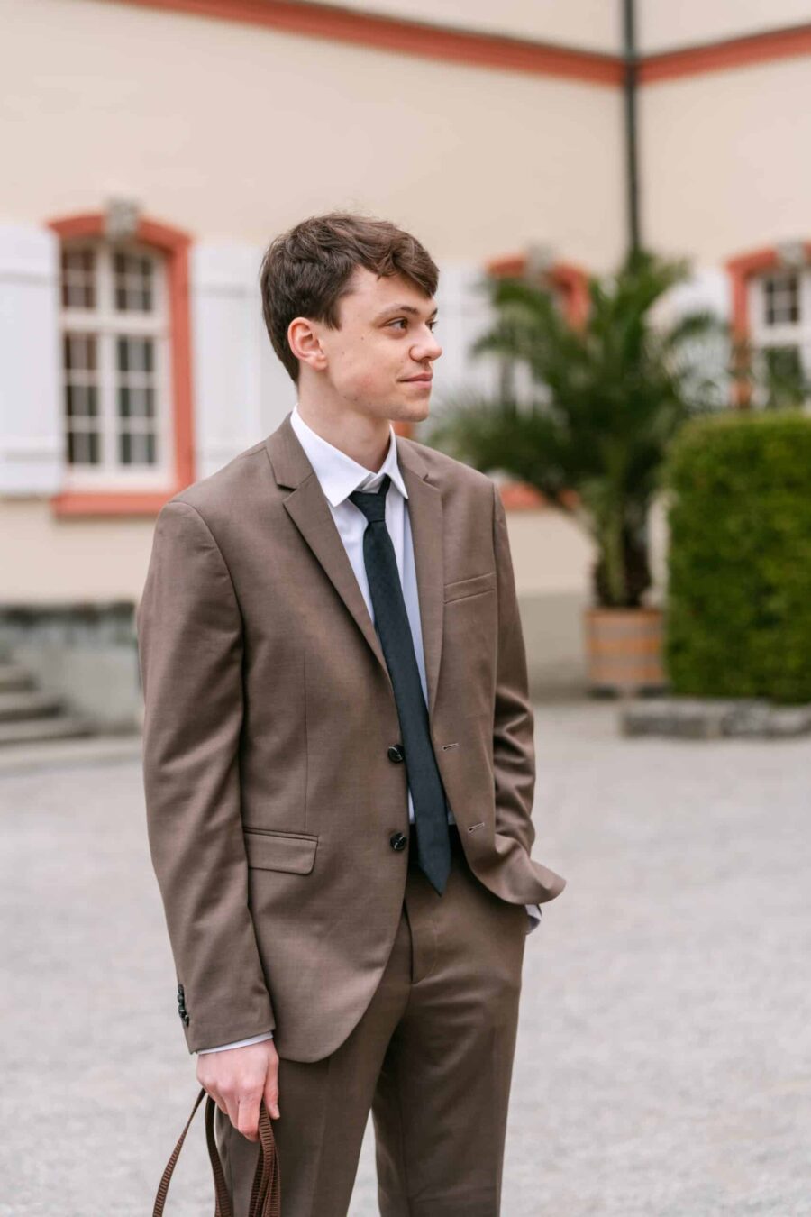 Hochzeitsgast im Anzug im Hof der Hochzeitslocation