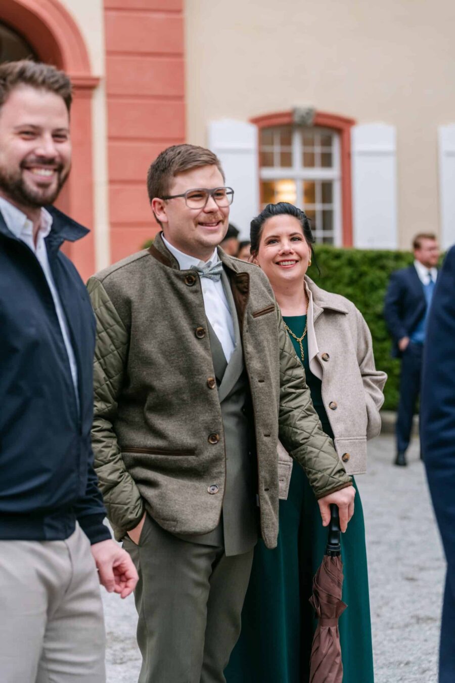 Hochzeit Insel Mainau Bodensee – Heiraten am Bodensee 182 Hochzeitsgäste lachen im Schlosshof mit Regenschirm