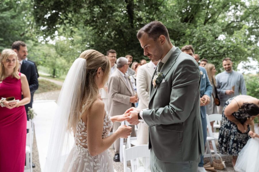 Brautpaar tauscht Ringe im Freien unter Bäumen