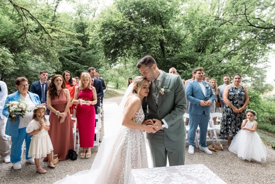 Brautpaar bei Trauung im Garten mit Gästen.