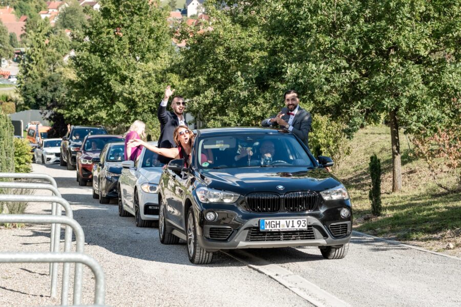 Hochzeitskonvoi auf Landstraße bei Sonnenschein.