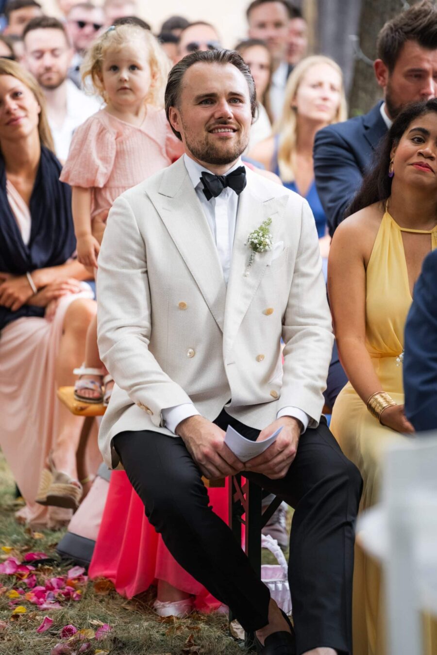 Gäste sitzen bei der Hochzeitszeremonie im Freien