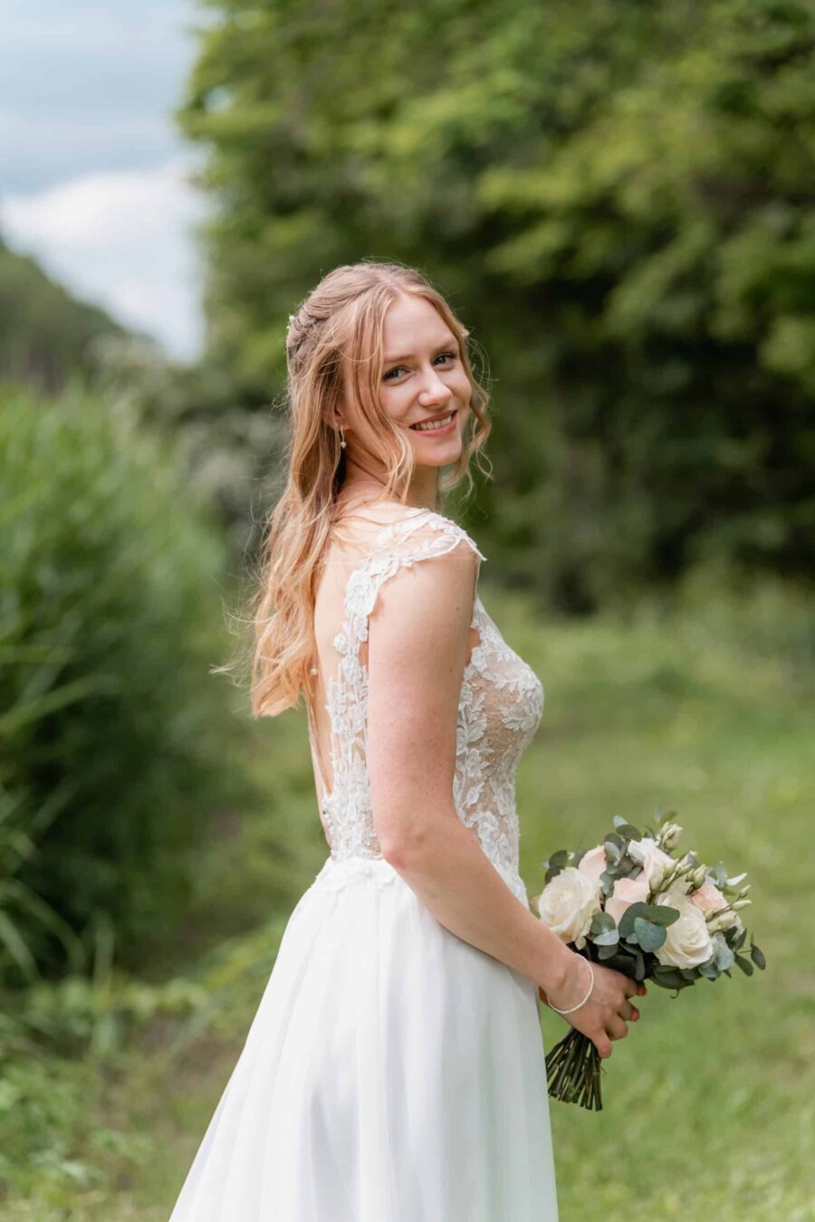 Braut mit Blumenstrauß im sommerlichen Garten