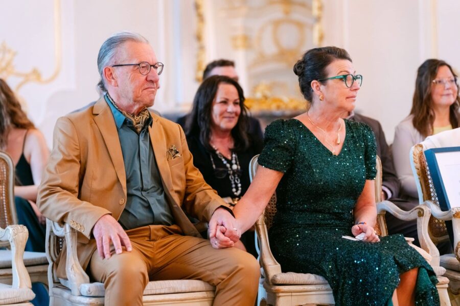 Hochzeit Insel Mainau Bodensee – Heiraten am Bodensee 70 Hochzeitsgäste sitzen Hand in Hand bei der Trauung