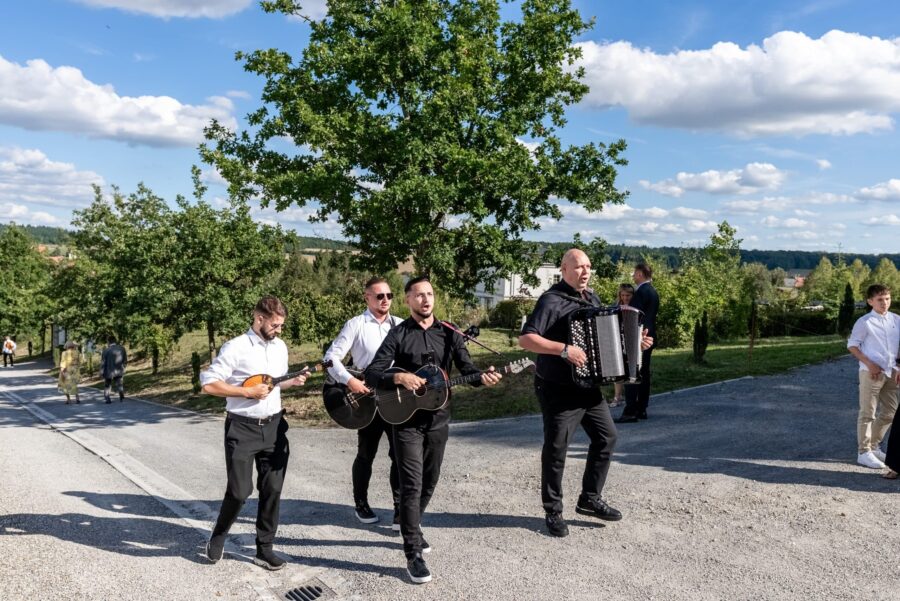 Musiker spielen bei sonniger Hochzeitsfeier im Freien.