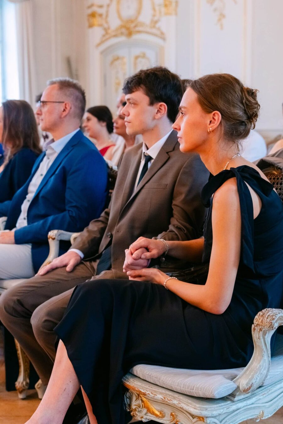 Hochzeitsgäste halten Hände im eleganten Trausaal