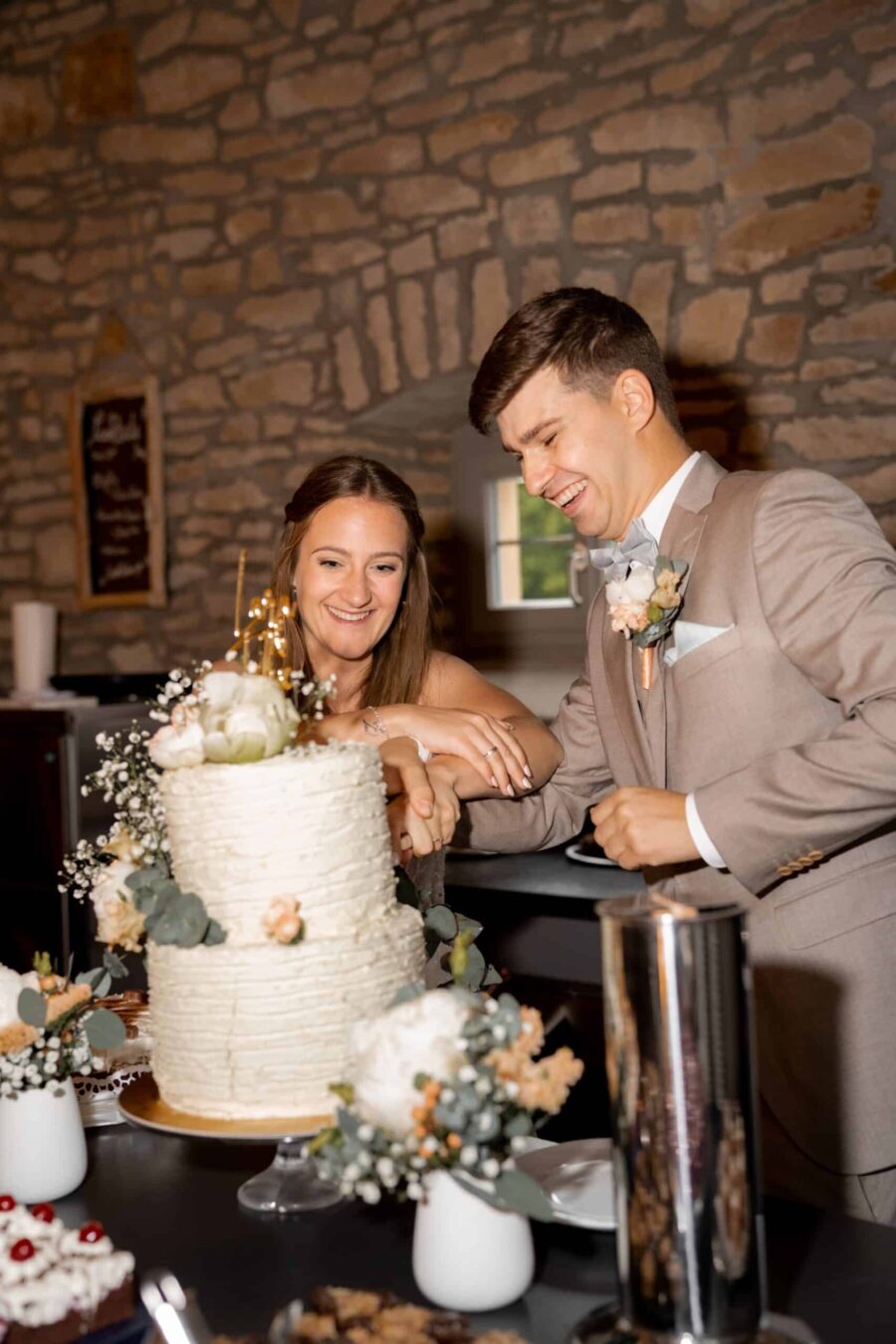 Brautpaar schneidet Hochzeitstorte in rustikaler Location.