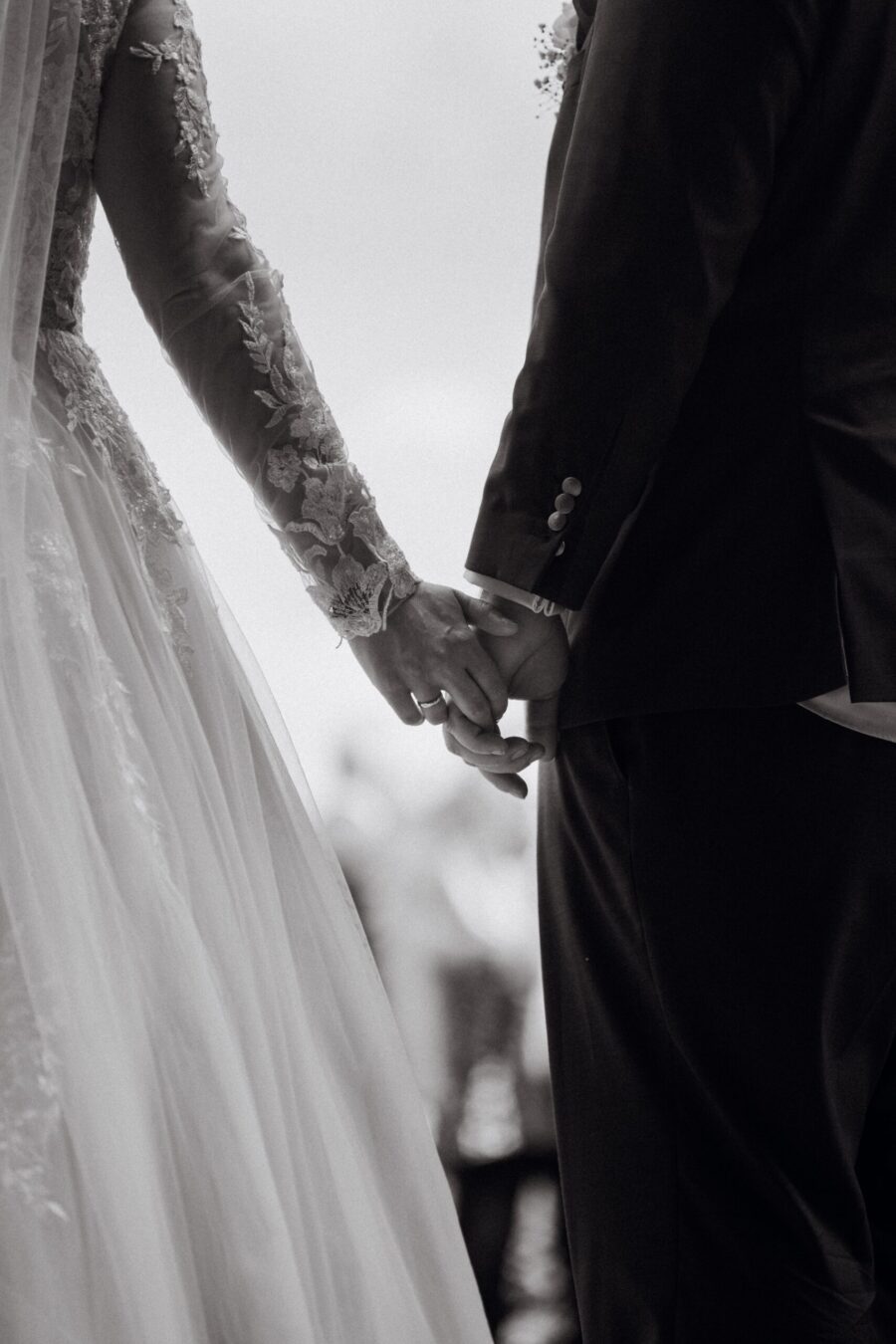 Brautpaar hält Händchen im Hochzeitskleidung